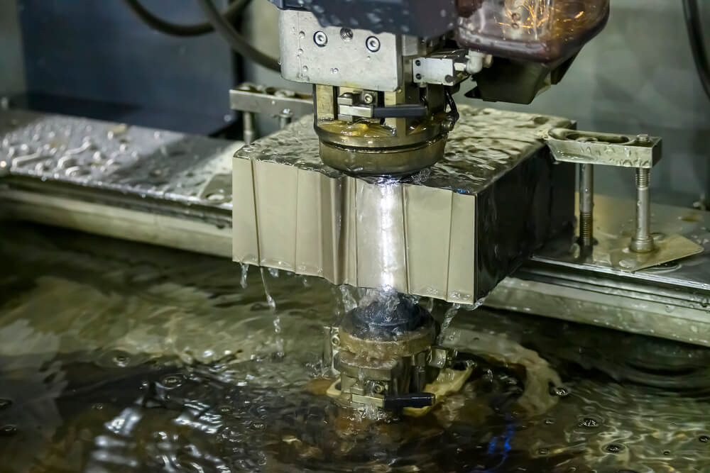 The Wire EDM machine cutting the die parts with liquid coolant — Photo